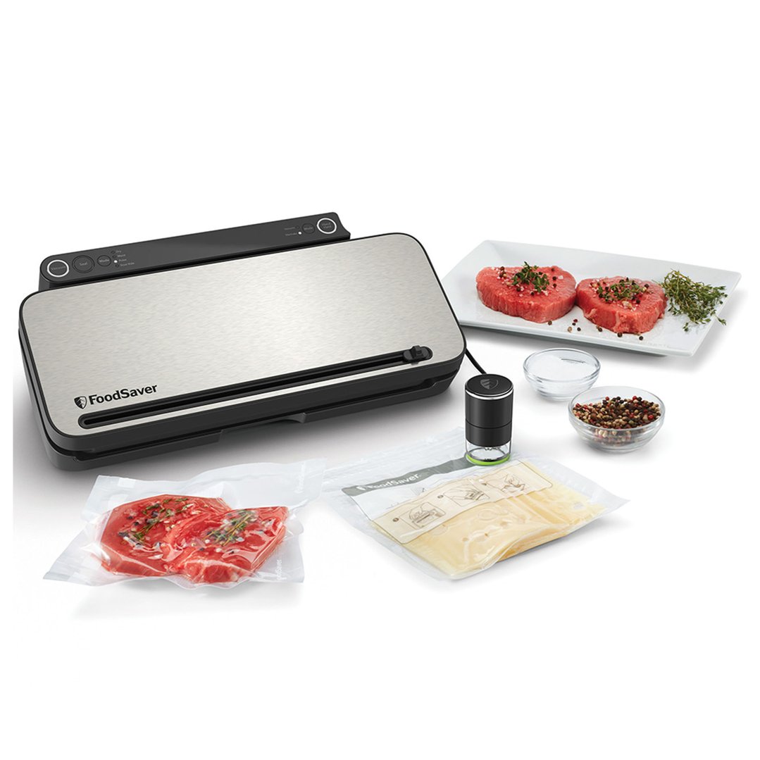 Food vacuum sealer with meat and cheese in vacuum bags and spices on a white background