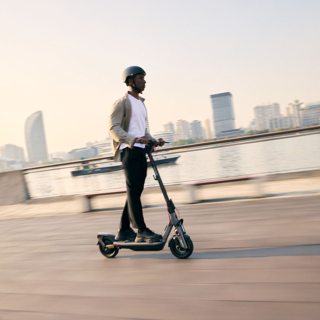 Man riding a Ninebot F3 PRO Electric KickScooter along a waterfront promenade