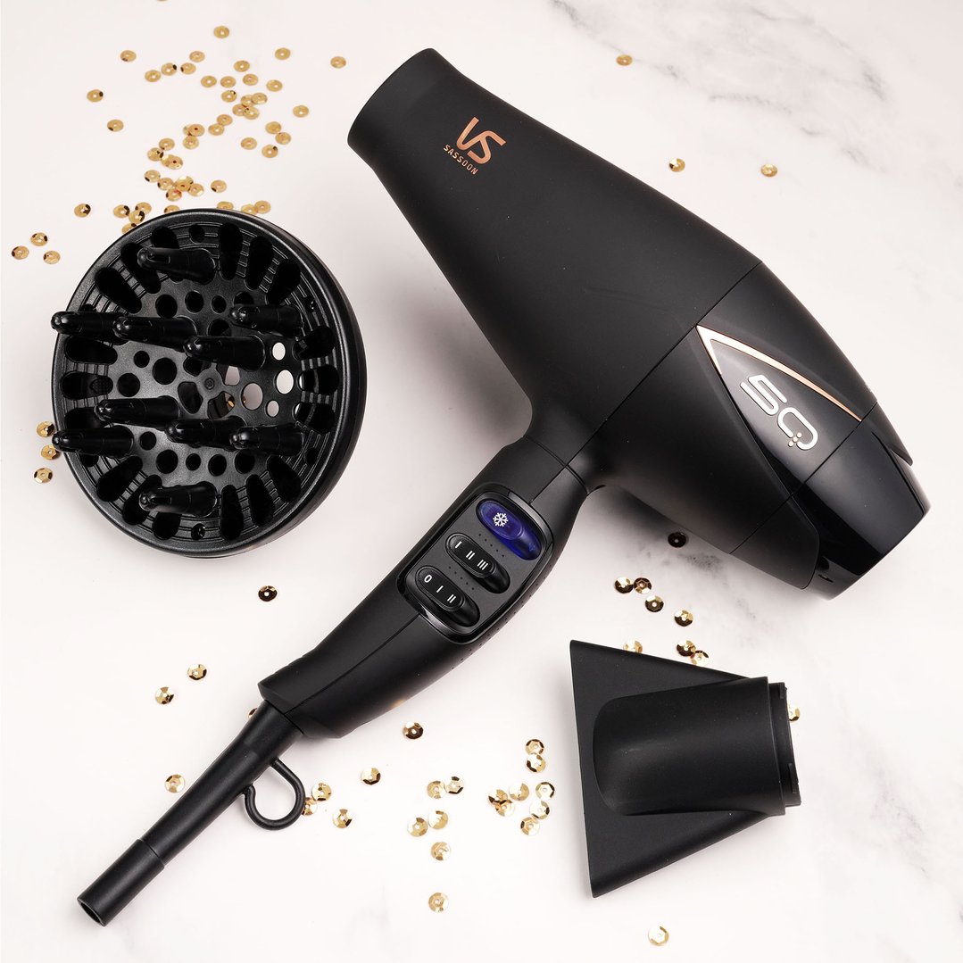 Black hair dryer with diffuser and concentrator nozzle on a marble surface