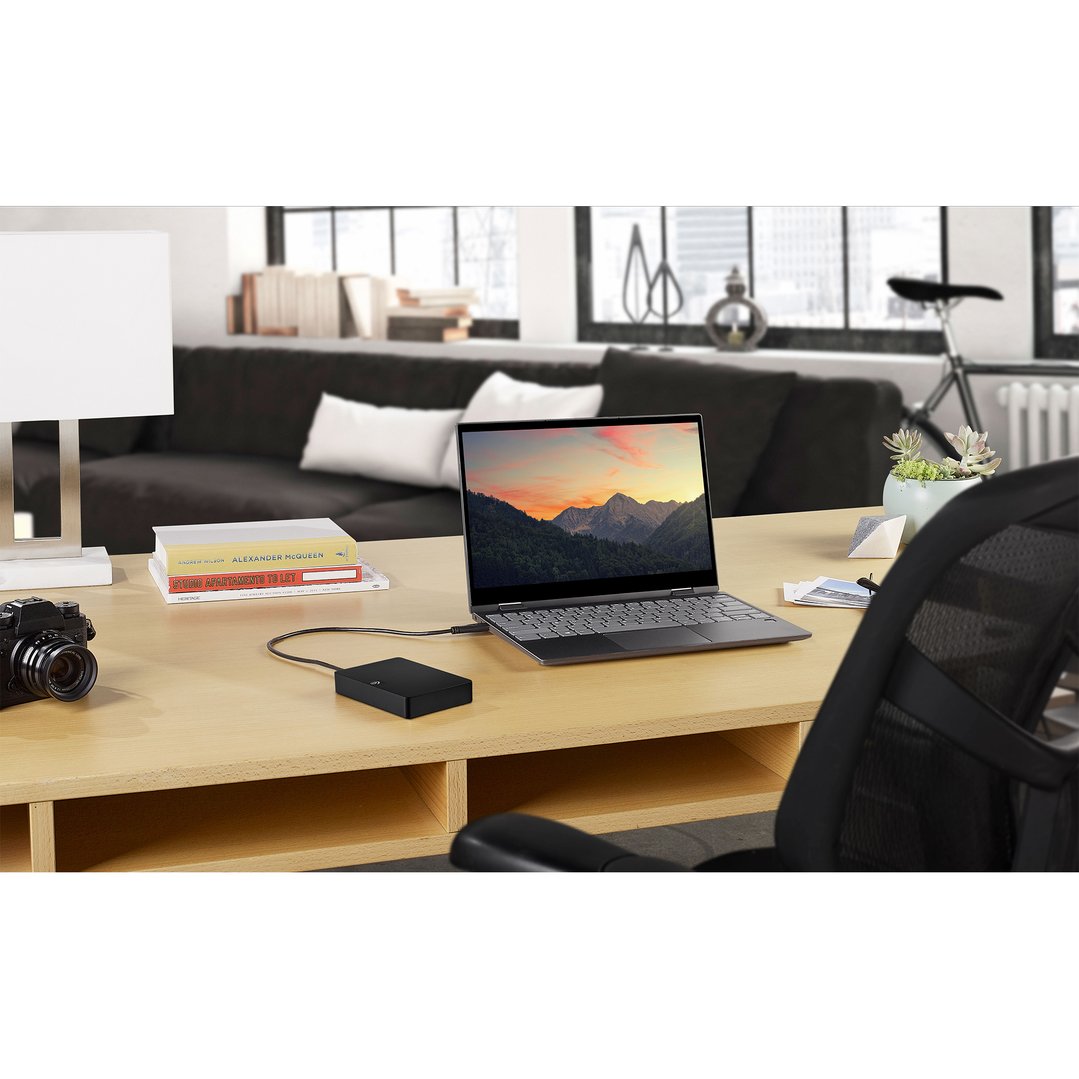 Seagate Expansion Portable Hard Drive connected to a laptop on a wooden desk