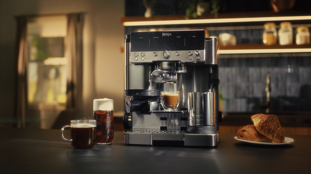 Ninja coffee machine making espresso, with coffee and croissants on a counter