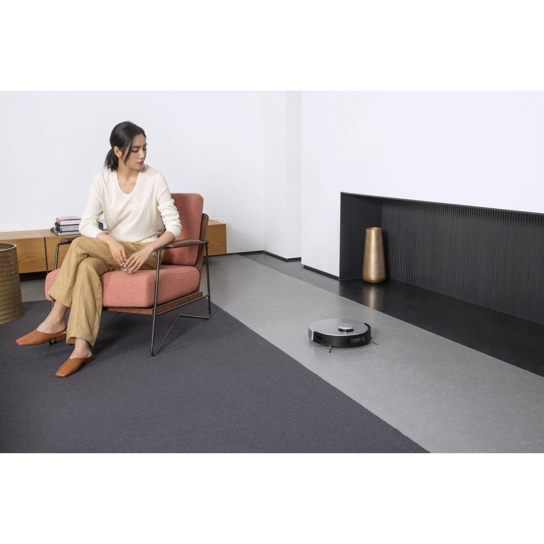 Woman sitting in a chair while a robotic vacuum cleans the floor
