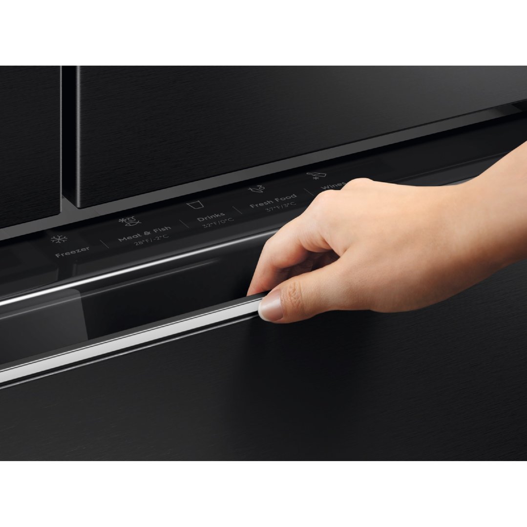 A hand opening the bottom drawer of a black French door fridge