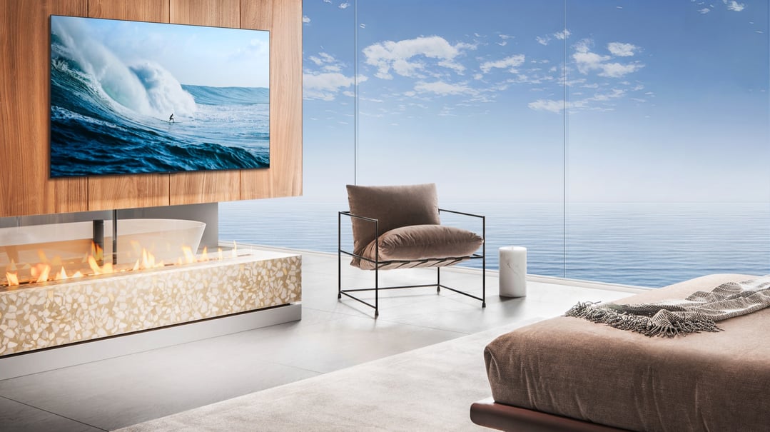 A TCL TV wall-mounted above a fireplace in a modern room with ocean views