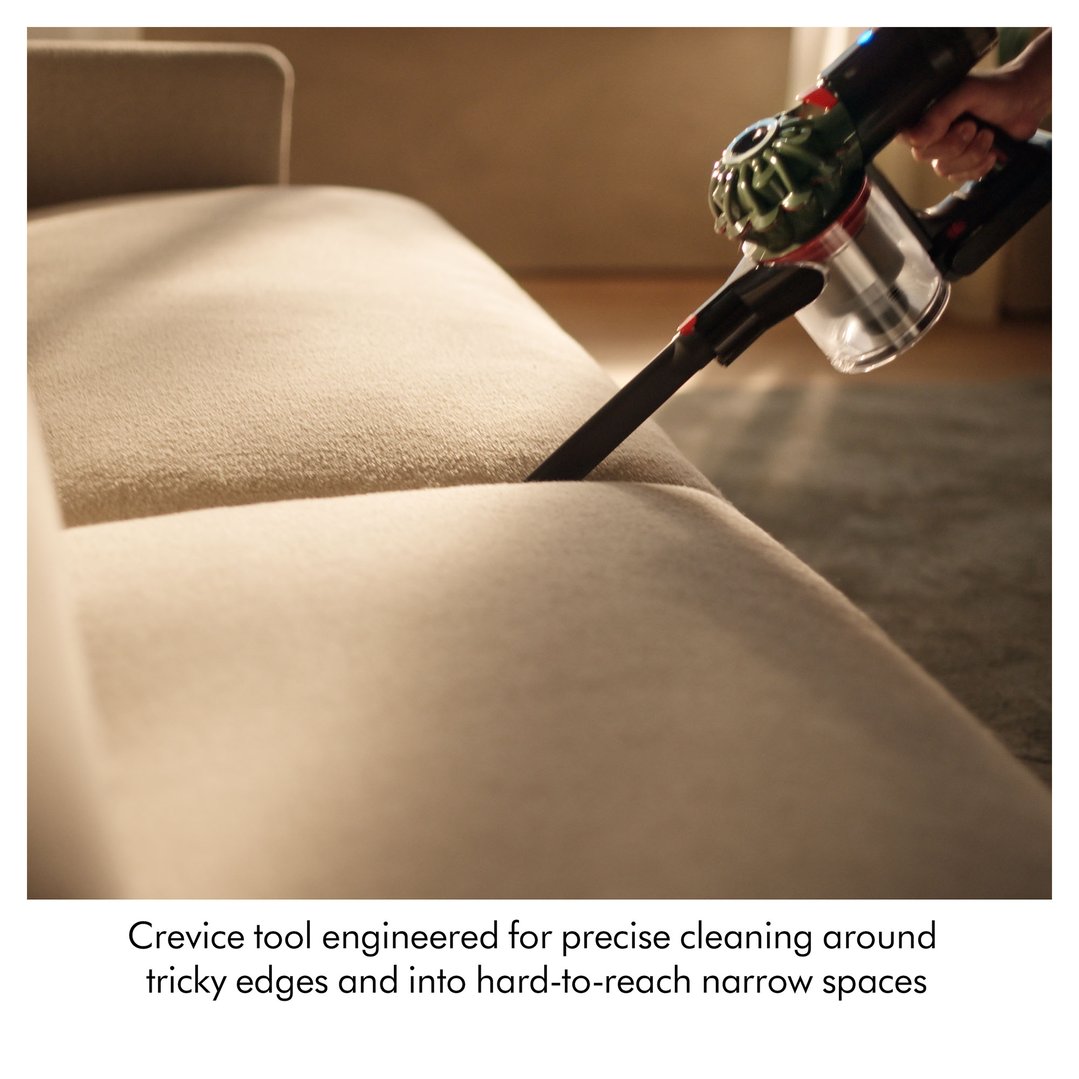 Handheld DYSON handStickVacuum with crevice tool cleaning between sofa cushions