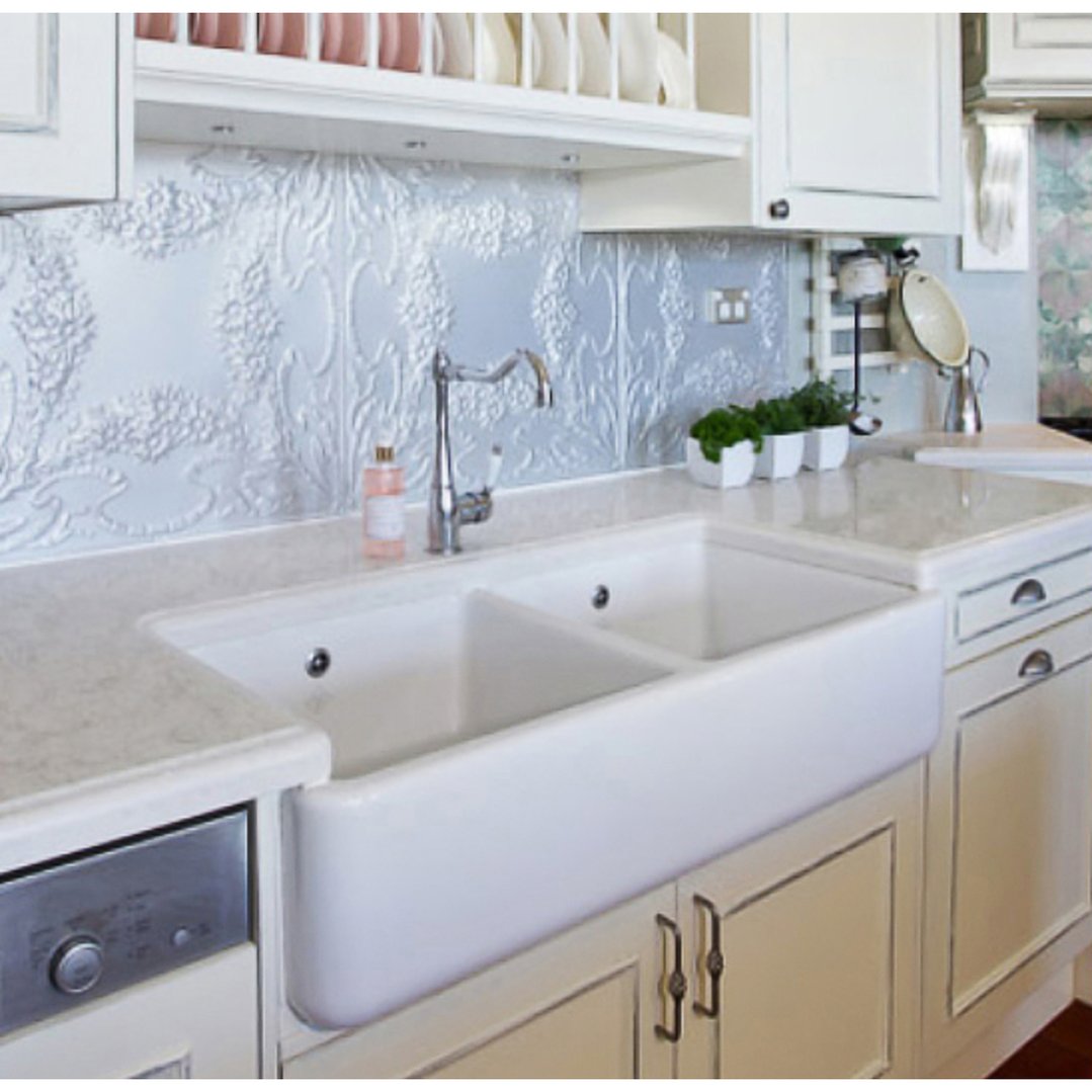 Double bowl sink in a white kitchen with patterned backsplash and dishwasher