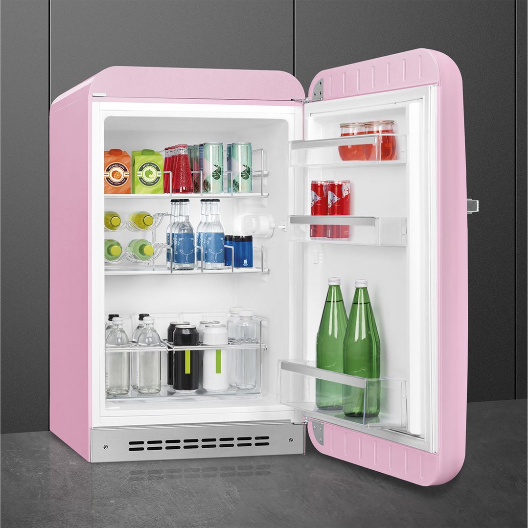 Pink SMEG FAB10 refrigerator with door open, filled with drinks, in a kitchen