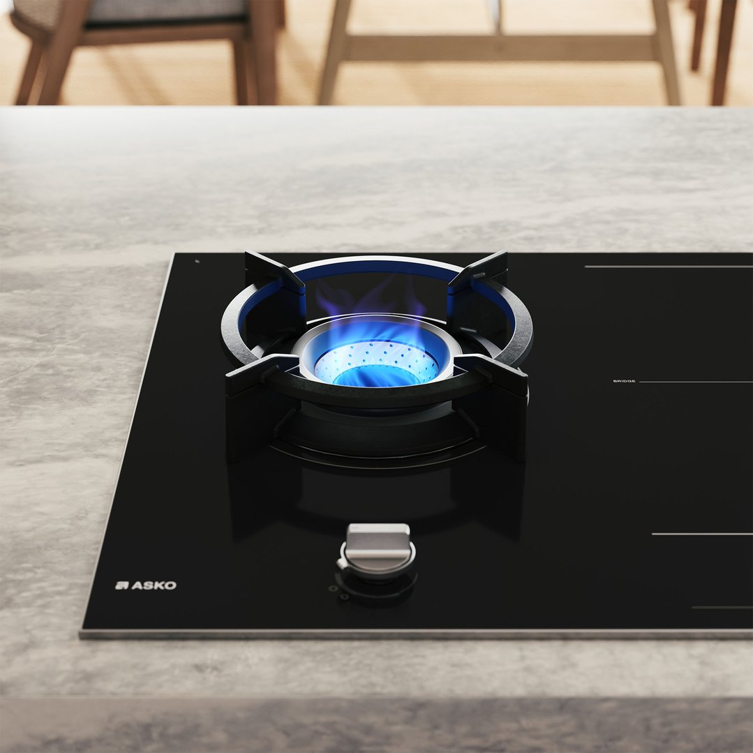 ASKO cooktop with a gas burner lit with blue flame in a kitchen setting