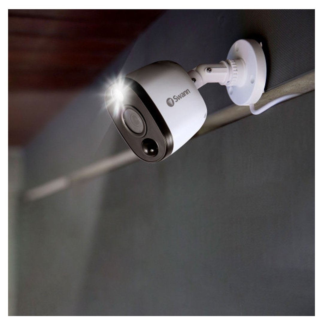 White security camera with a bright spotlight mounted on a dark wall