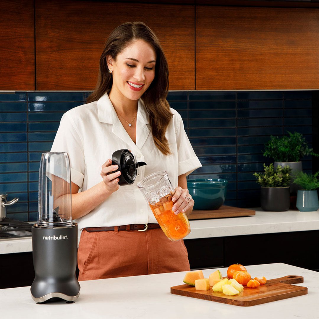Woman preparing a smoothie with a NUTRiBULLET blender in a kitchen