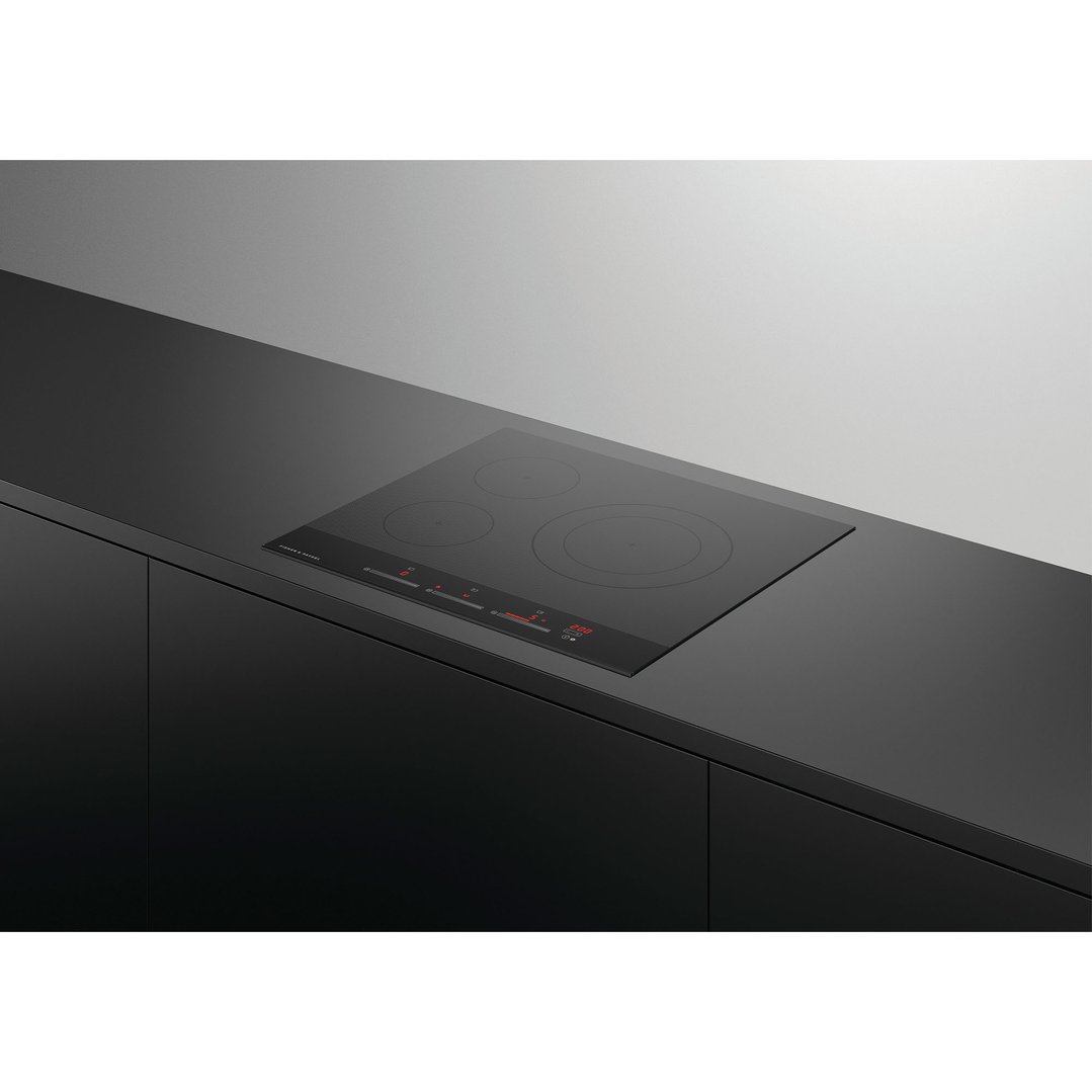 Black induction cooktop with three zones built into a dark kitchen counter