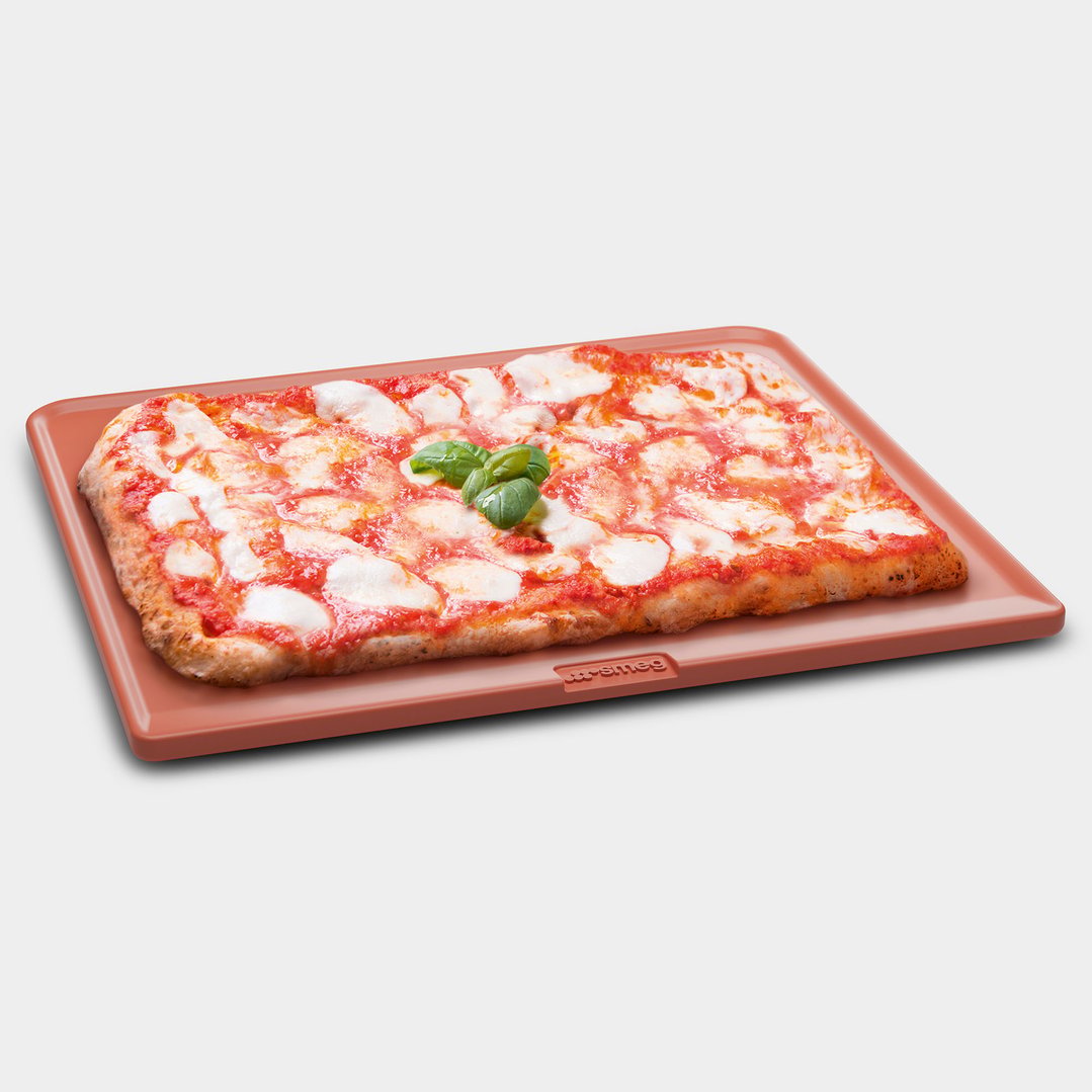 Rectangular pizza with basil on a terracotta-colored refractory stone