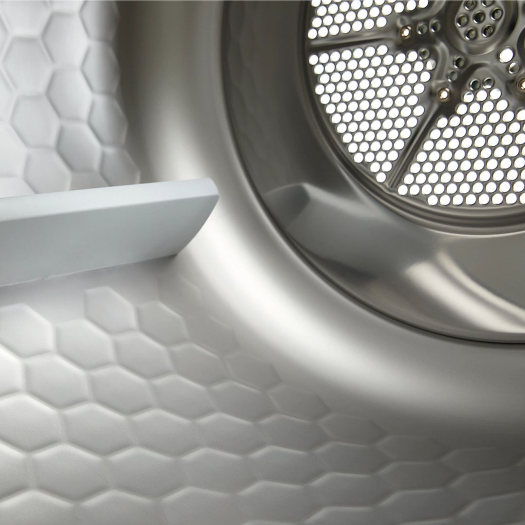 Close-up of a washing machine drum and honeycomb-patterned side panel