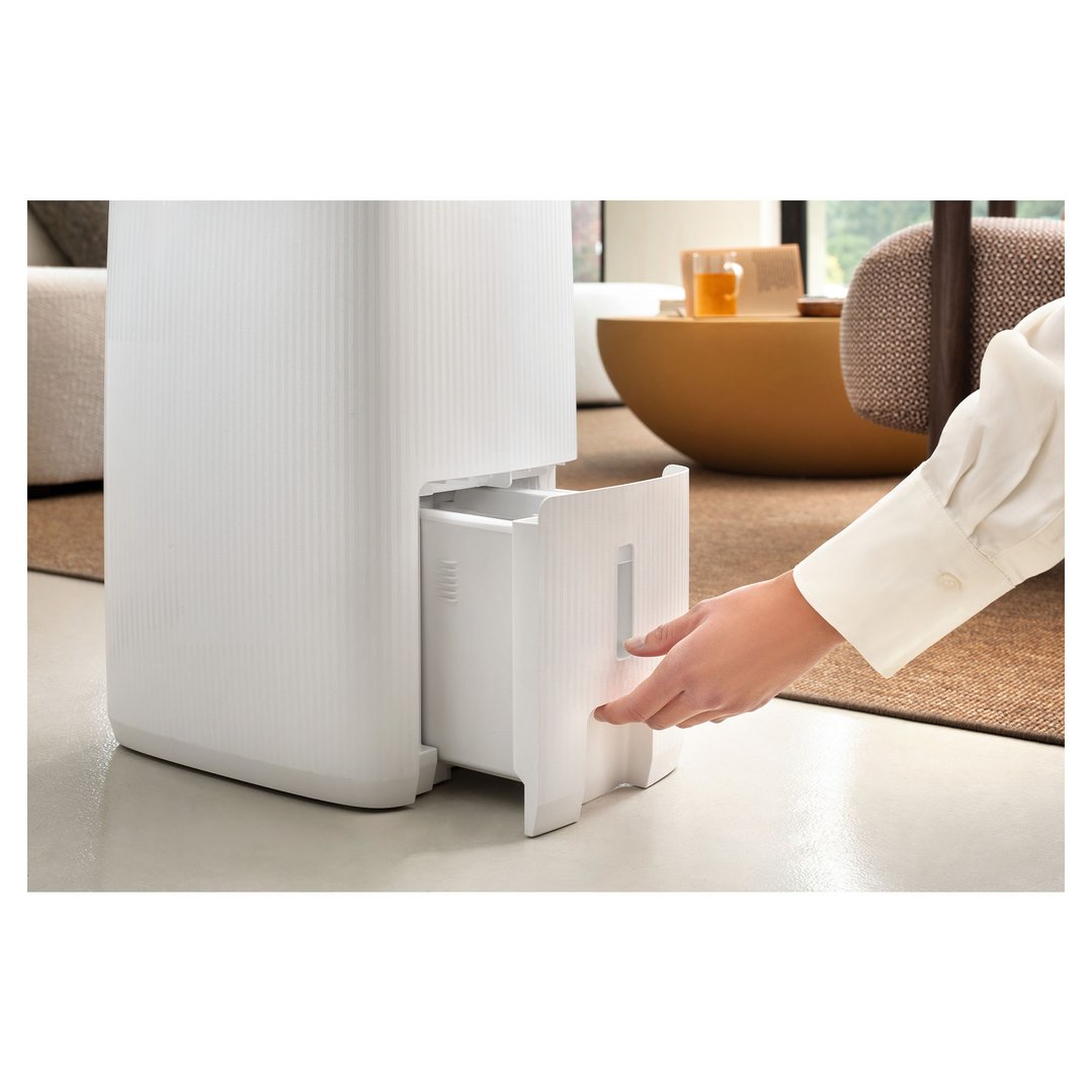 A person's hand pulling out the water tank from a white De'Longhi dehumidifier