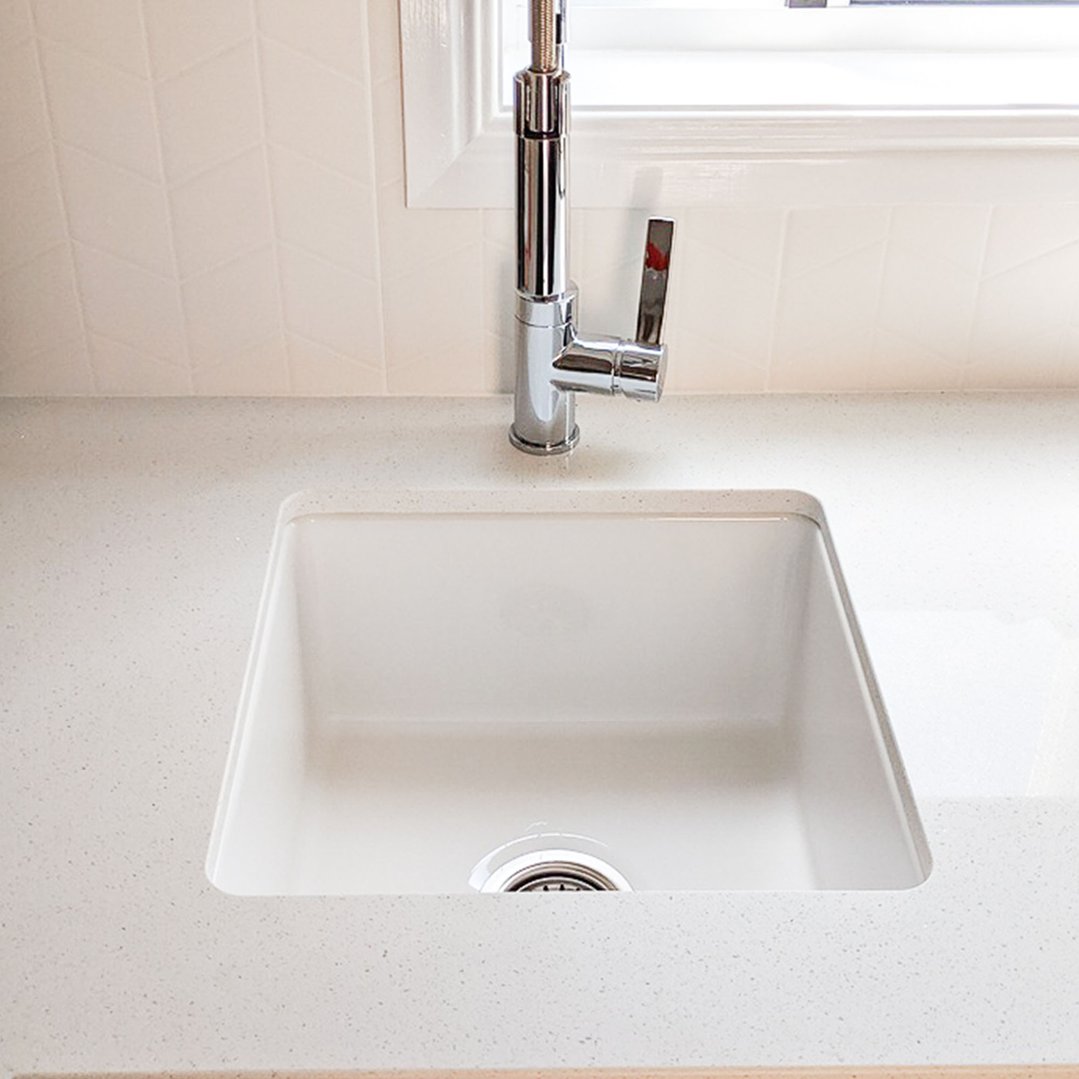 White kitchen sink with a chrome faucet and light speckled countertop