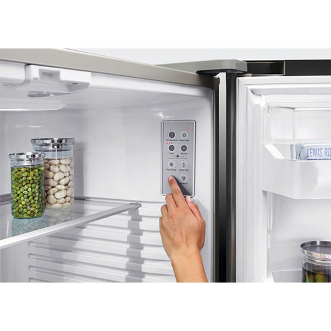 Hand adjusting the internal control panel of a French Door Refrigerator Freezer