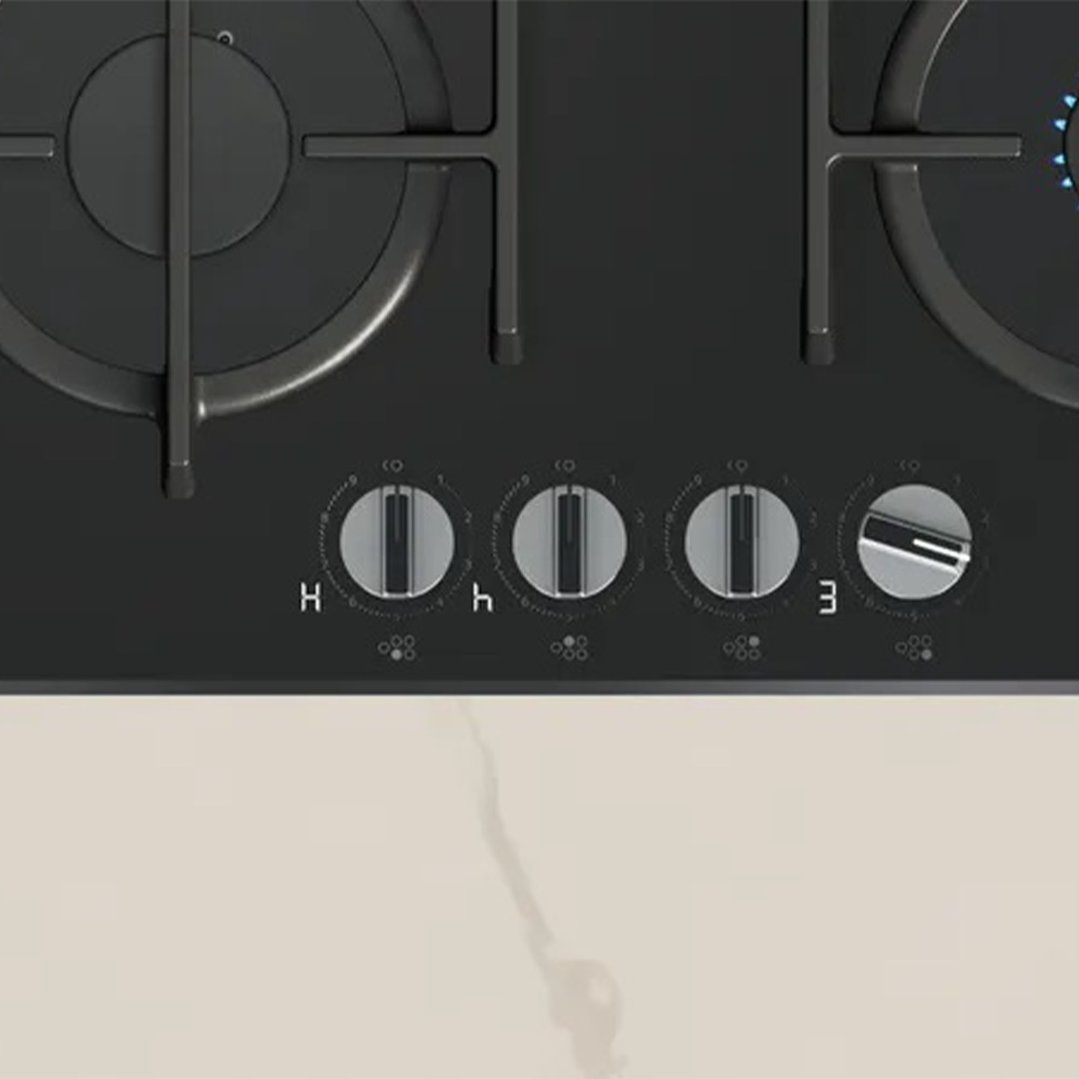 Black cooktop with four burners and control knobs on a light countertop