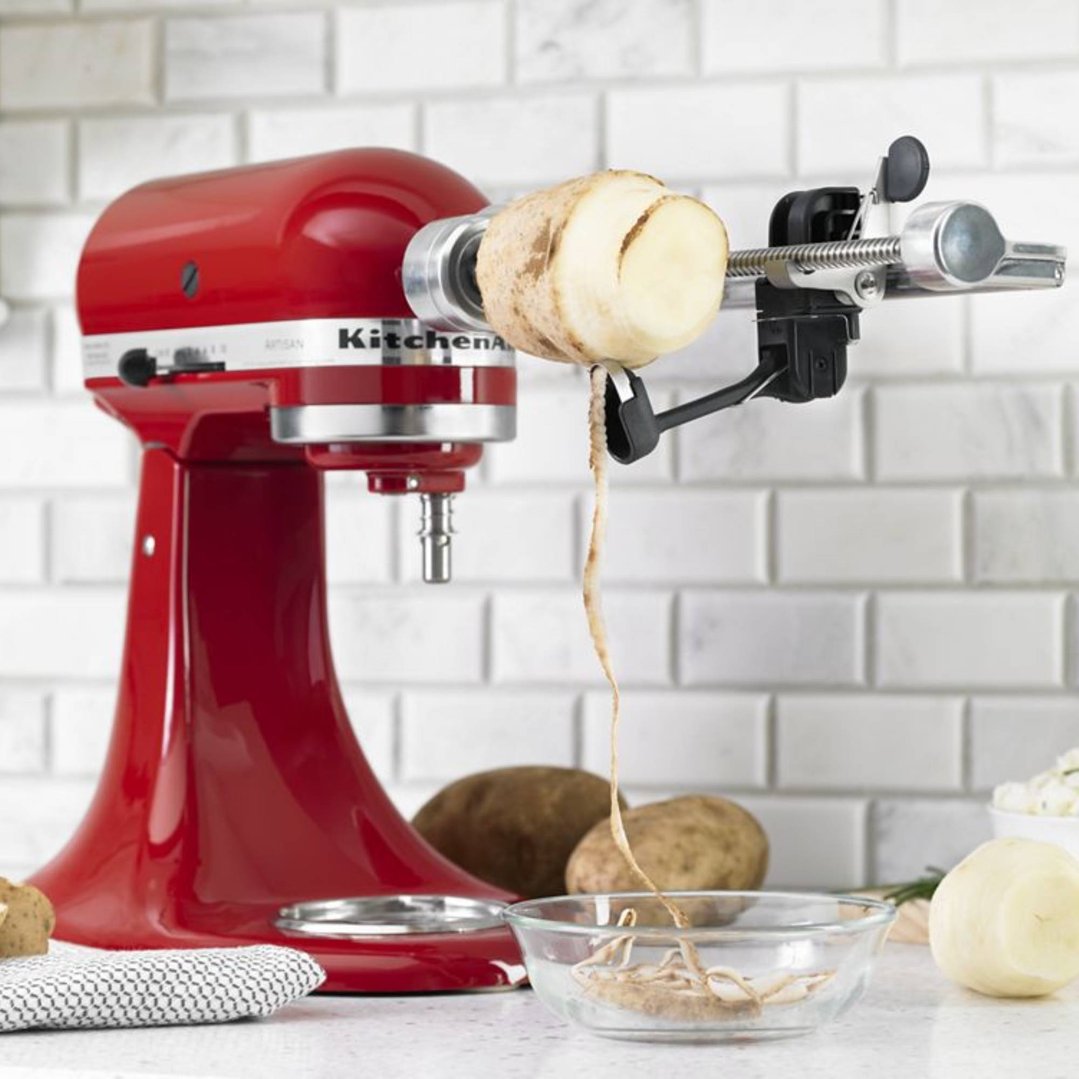Red KitchenAid stand mixer with spiralizer attachment peeling a potato