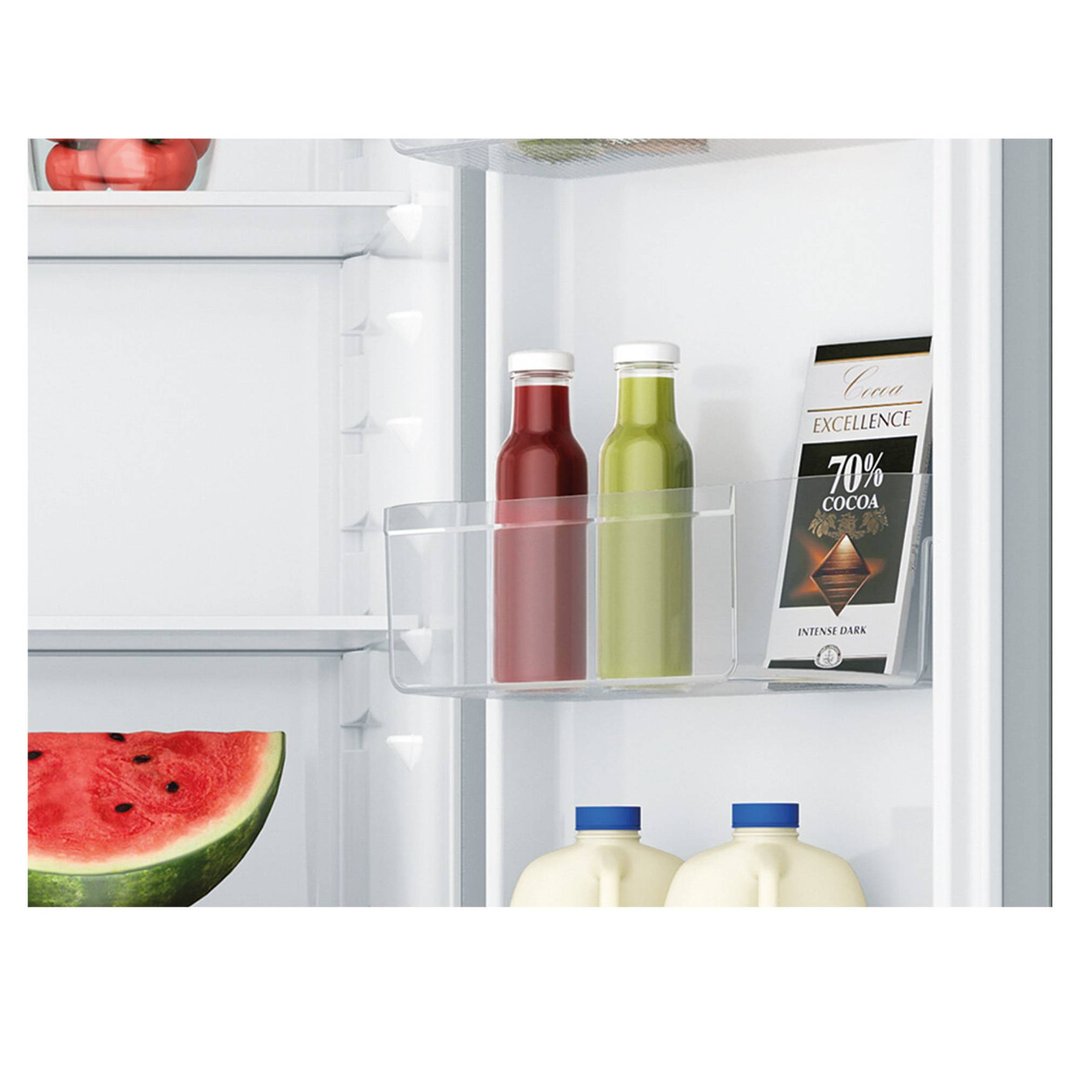Interior of a refrigerator with watermelon, bottles, and chocolate on shelves