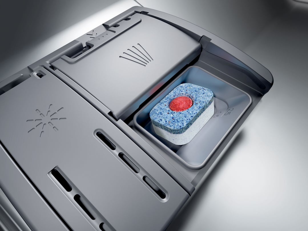 Close up of a dishwasher detergent dispenser with a tablet inside