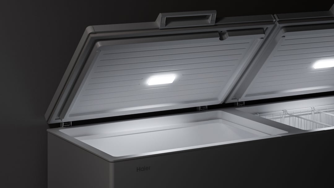 Open chest freezer with interior lights on in a dark setting