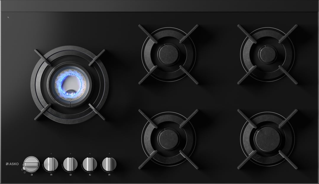 Overhead view of a black gas cooktop with one burner lit
