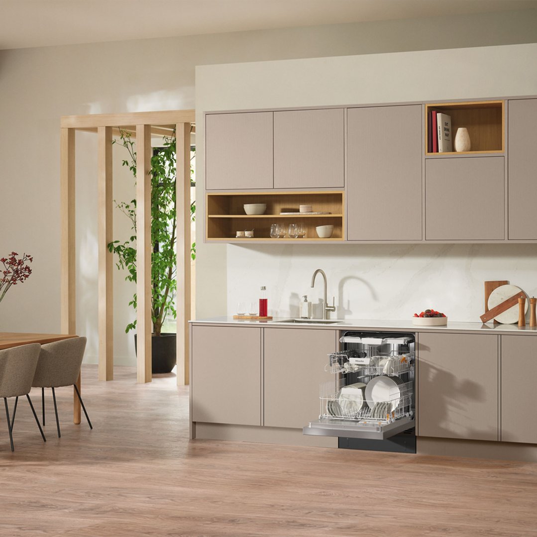 A Miele dishwasher with its door open in a modern kitchen setting