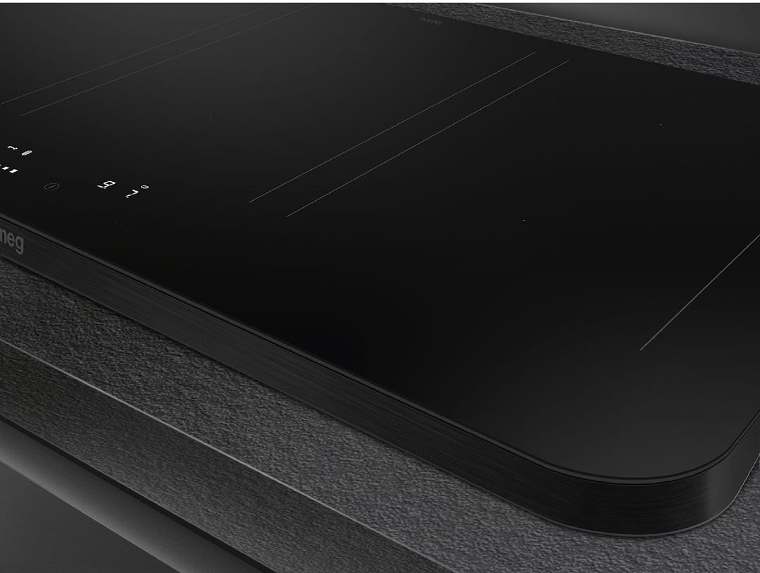 Close up of a black induction cooktop on a dark textured countertop