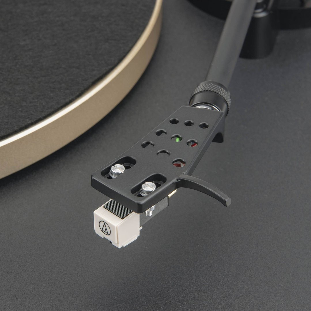 Close-up of a turntable's tonearm and cartridge on a dark surface