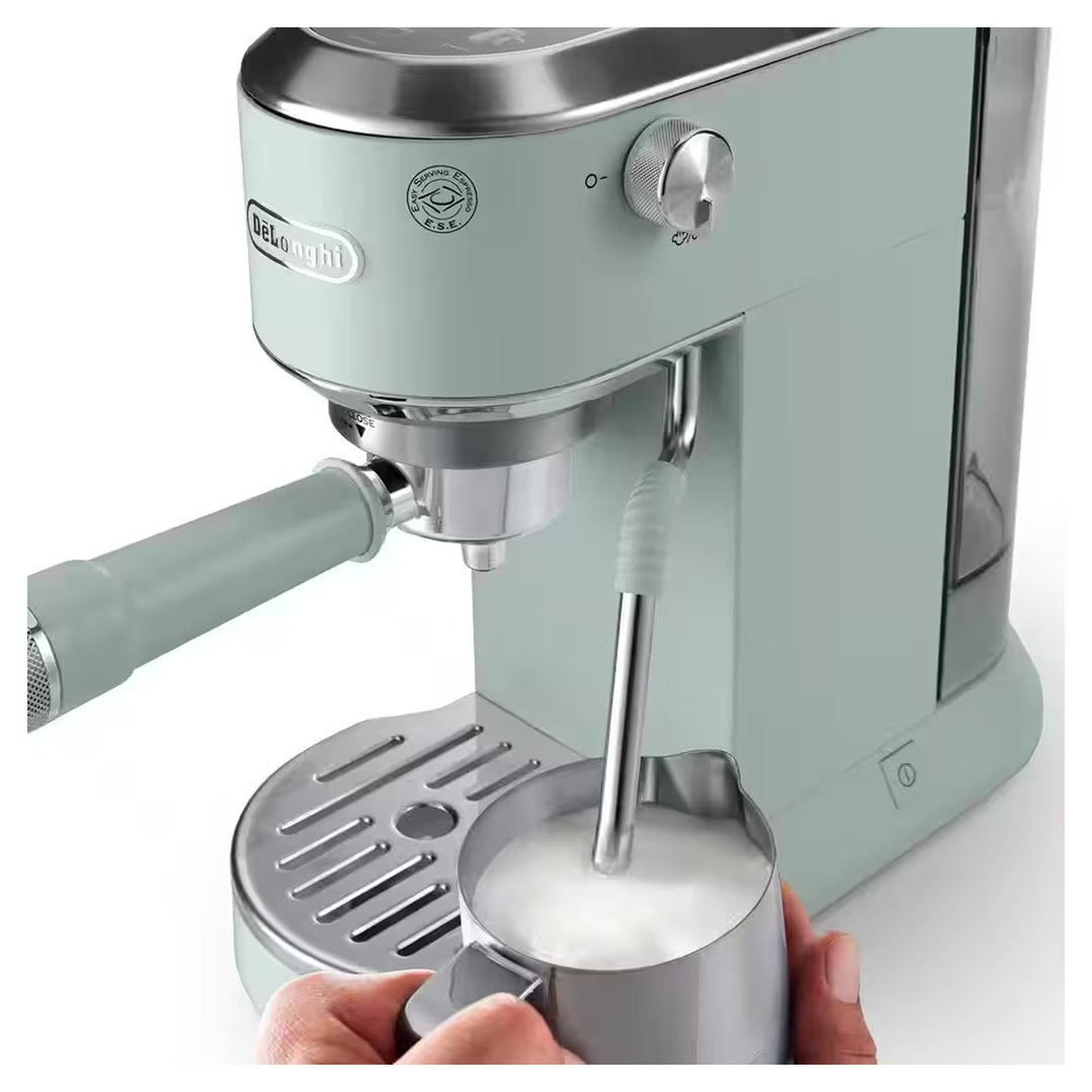 Hands holding a milk frothing jug under the coffee machine's steam wand