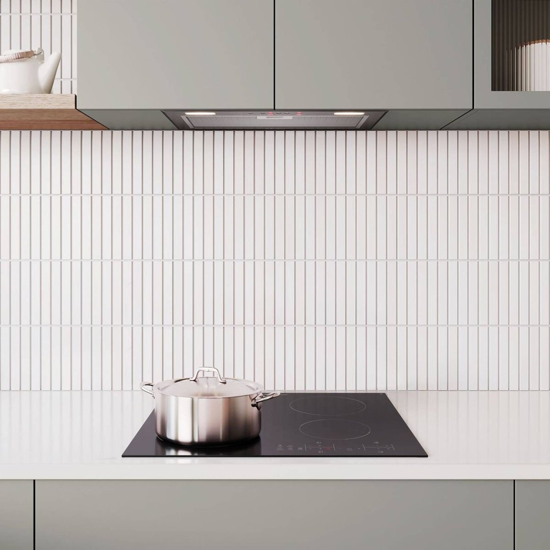 A stainless steel pot on a black ceramic cooktop in a modern kitchen