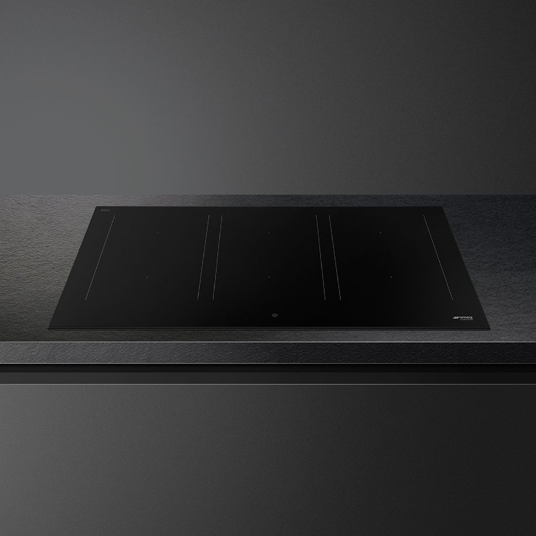 Black induction cooktop integrated into a dark countertop in a modern kitchen