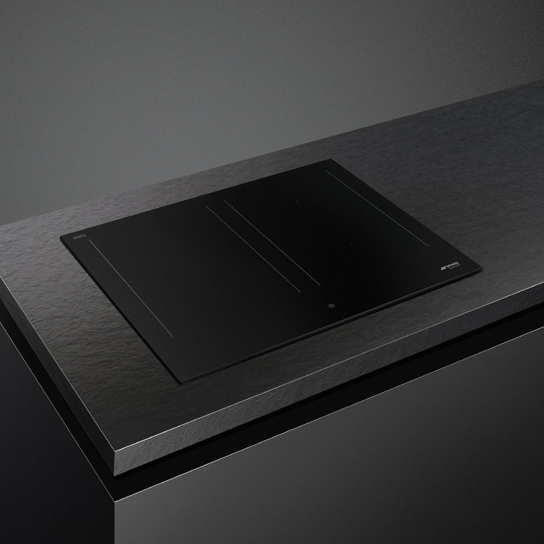 Matte black induction cooktop integrated into a dark countertop in a modern kitchen