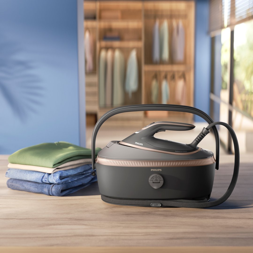 Philips PerfectCare Steam Generator 8000 Series iron on a wooden table with folded clothes