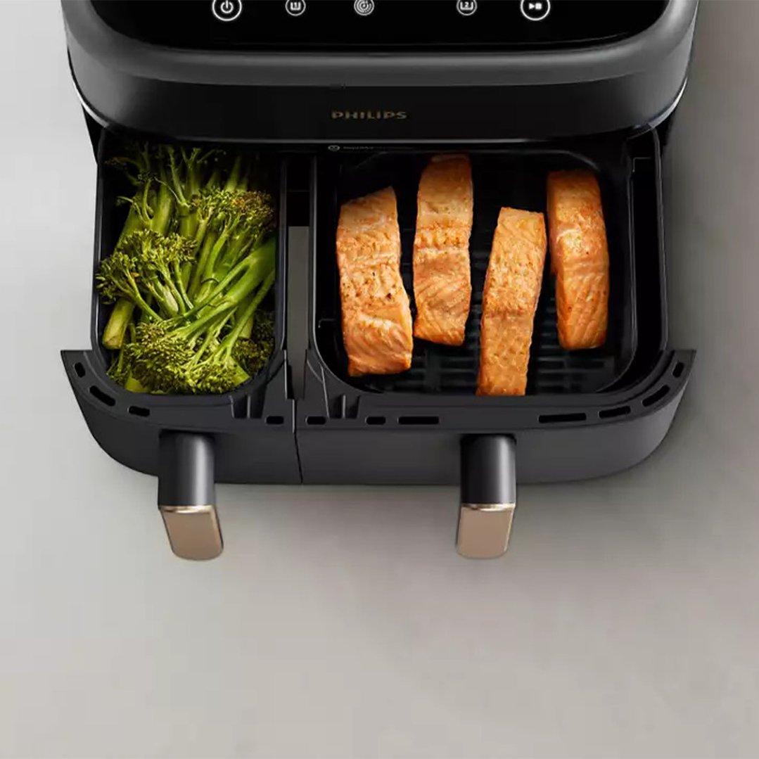 Overhead view of a Philips airfryer with broccoli and salmon in its baskets