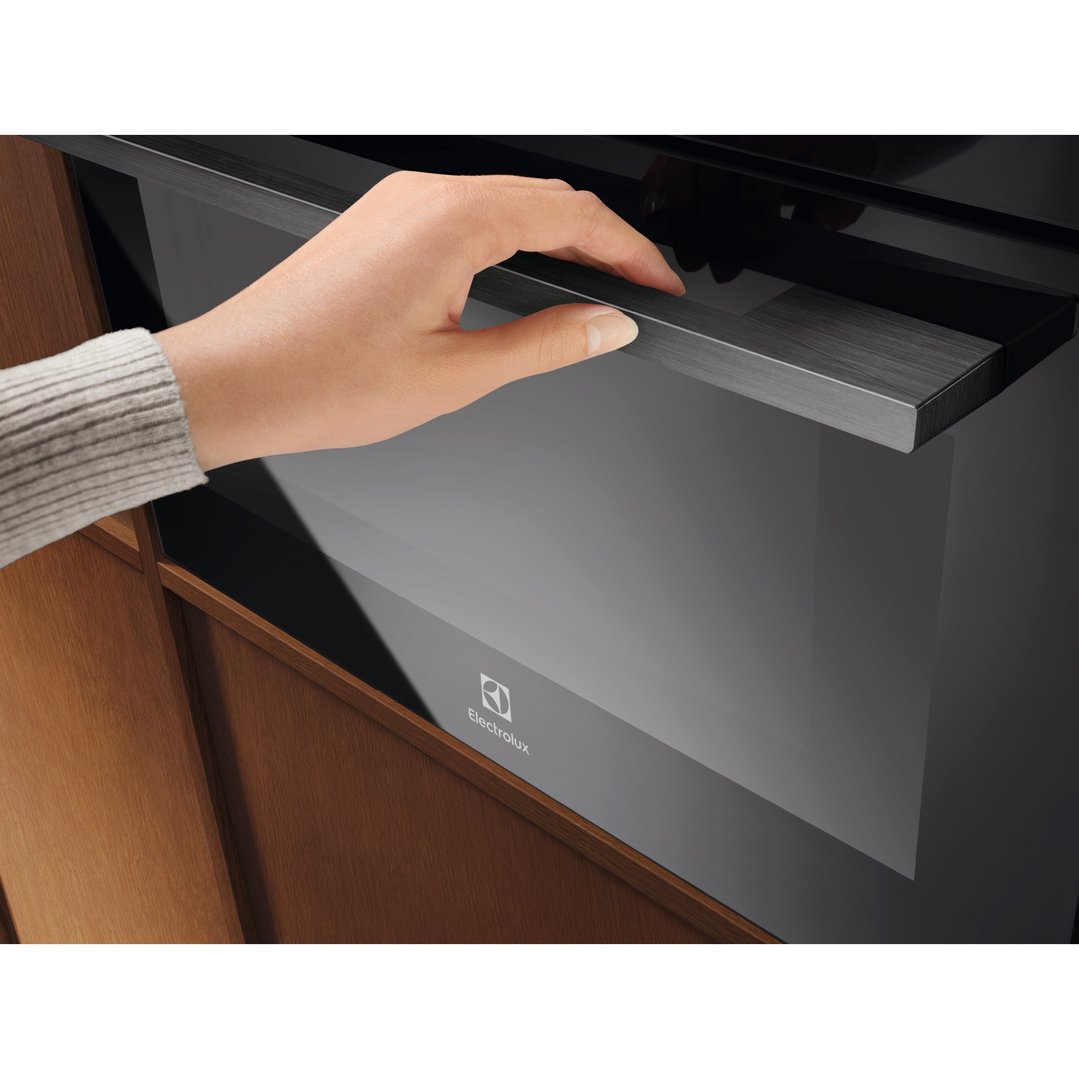 Hand opening the door of a built-in Electrolux compact combi microwave oven