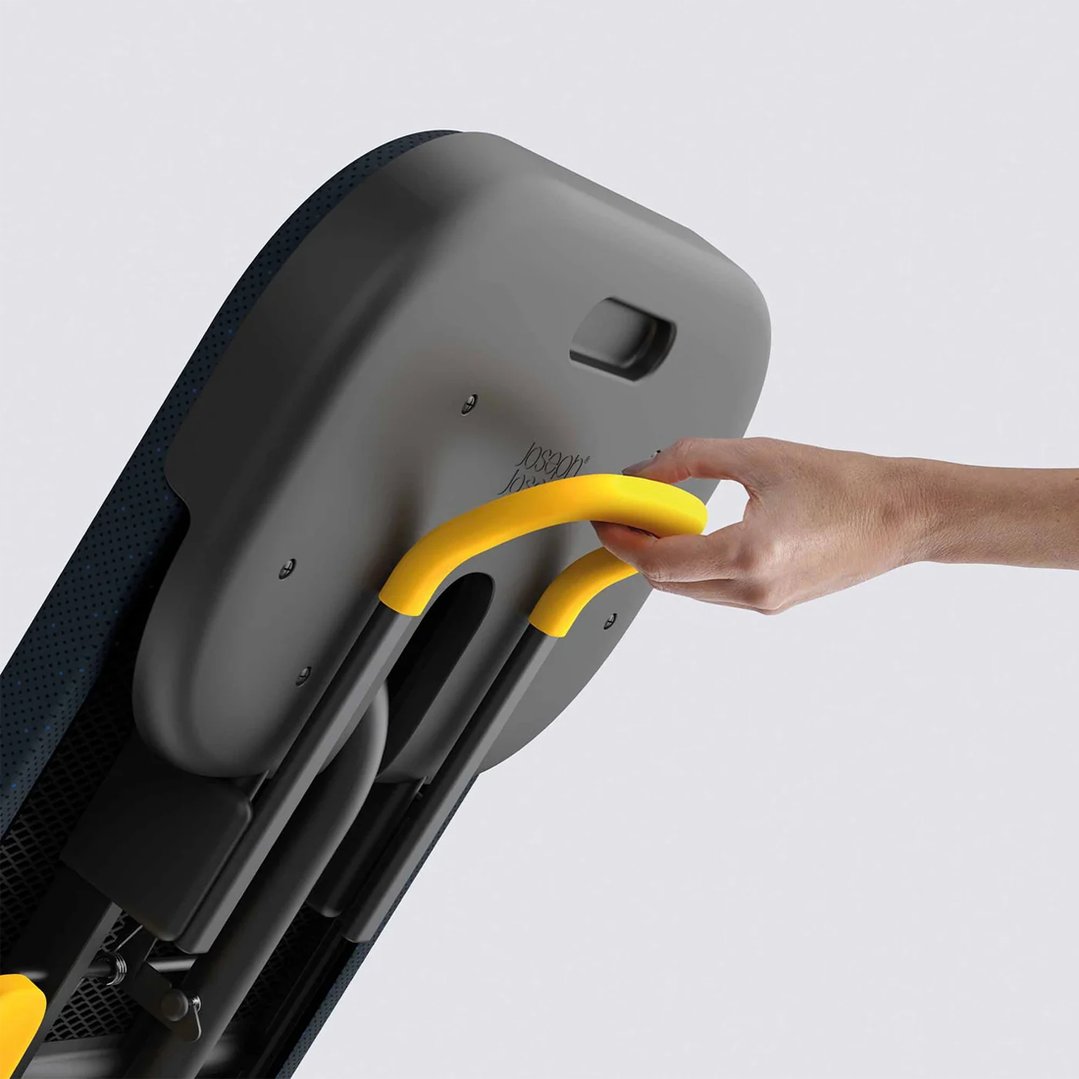 Hand holding the yellow handle of a folded ironing board