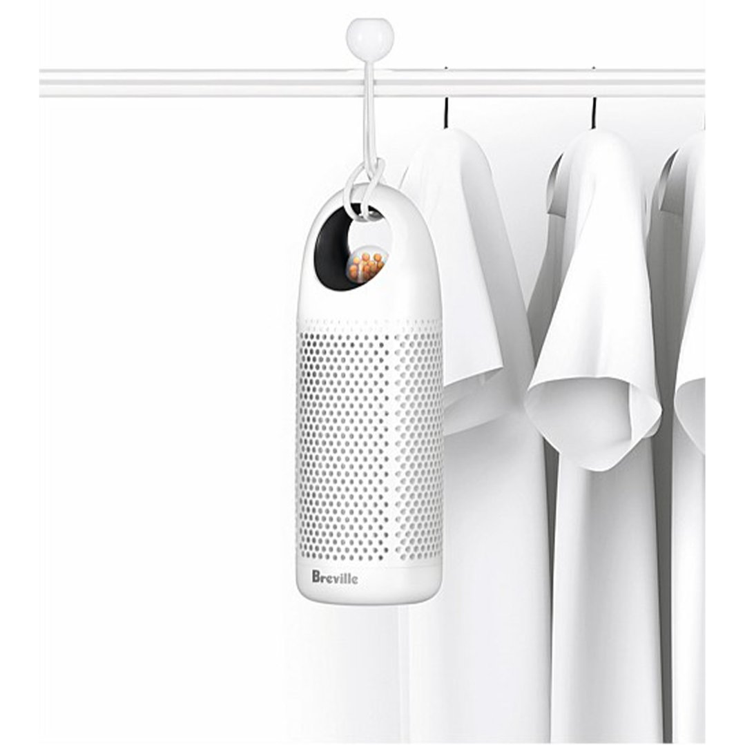 Breville dehumidifier hanging on a rail with white shirts in a closet