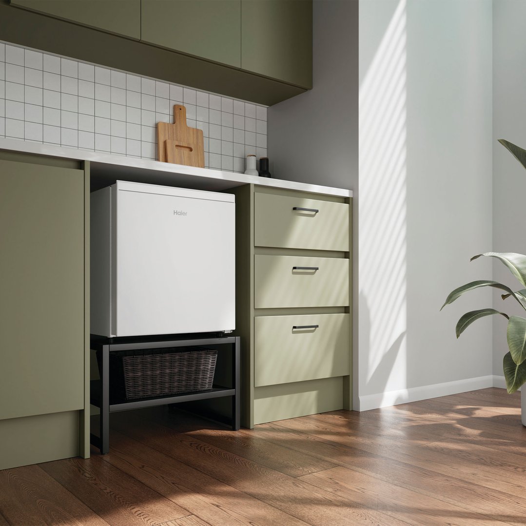 Haier bar refrigerator on a stand in a modern kitchen with green cabinets