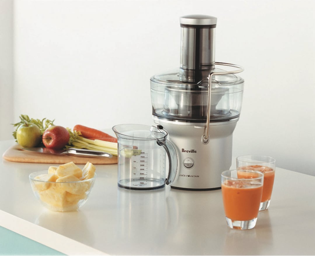 Breville Juice Fountain juicer on a counter with fruit, vegetables, and juice