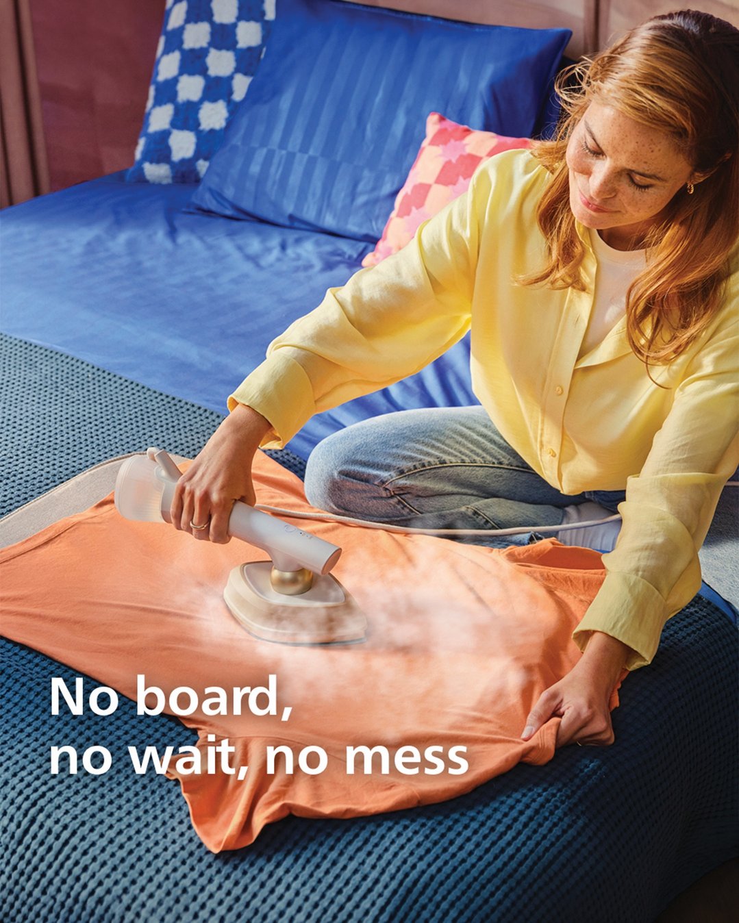 Woman steaming an orange t-shirt with a Philips hybrid iron and steamer