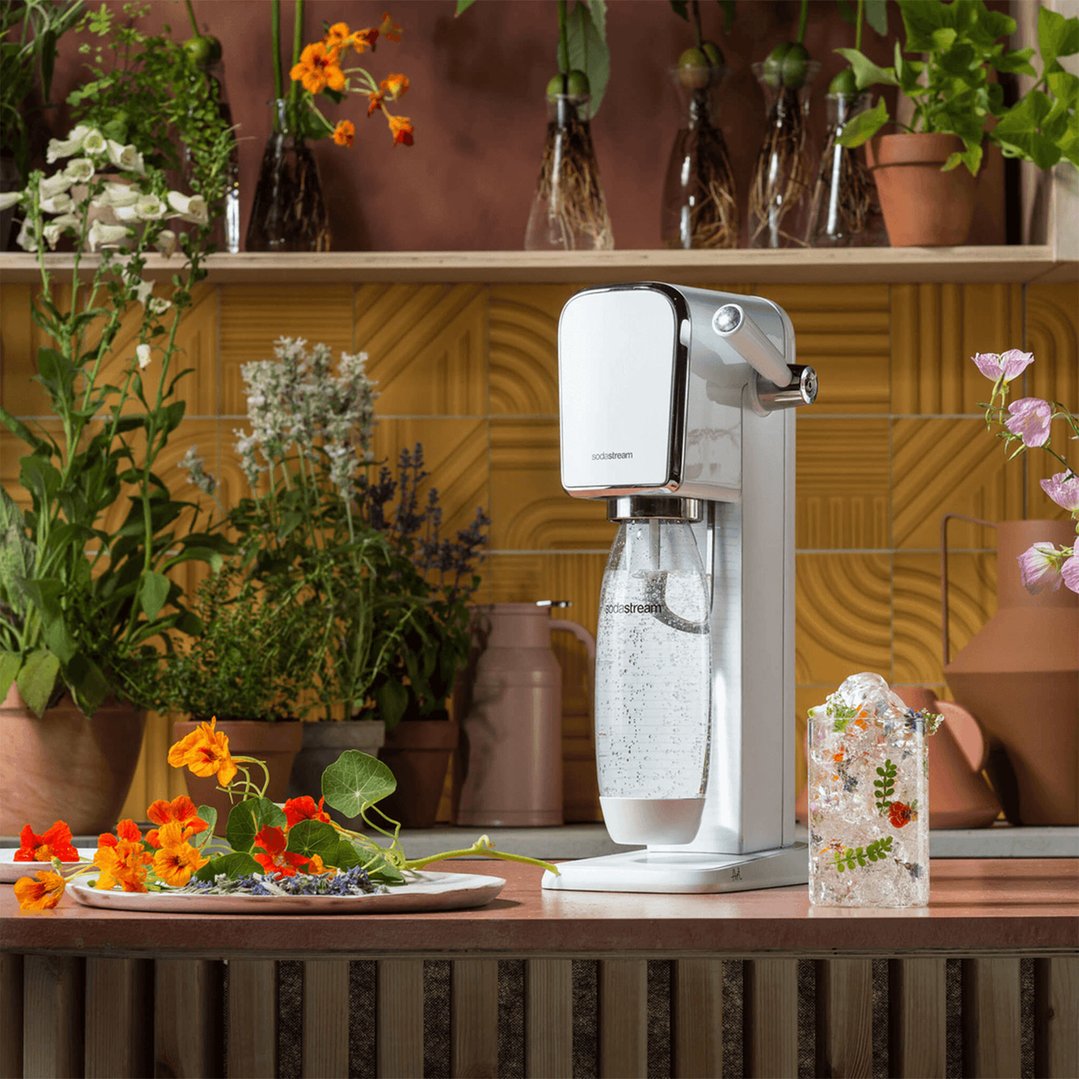 White SodaStream Art Sparkling Water Maker on a counter with plants and flowers