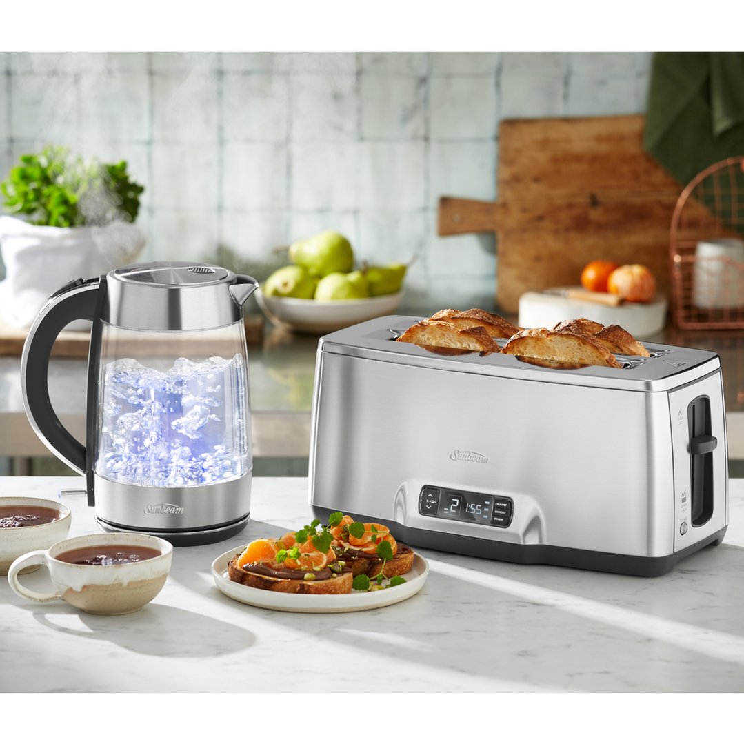 Glass kettle and toaster on a kitchen counter with food and drinks