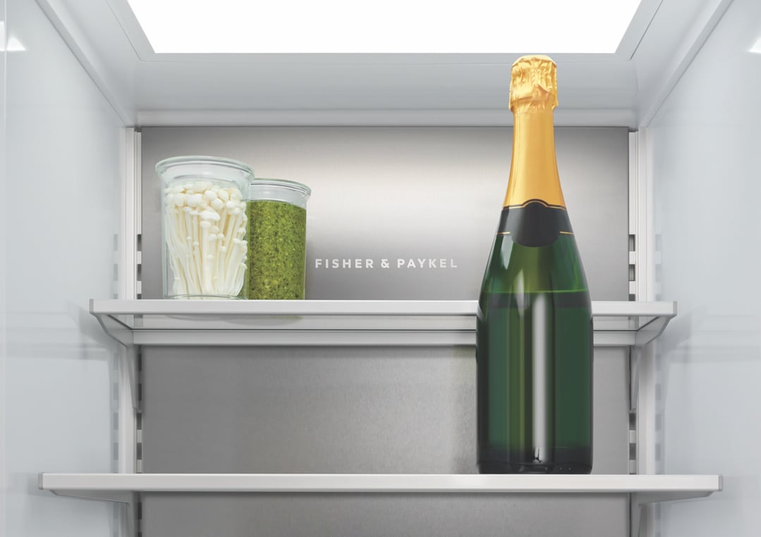 Open Fisher & Paykel refrigerator interior with champagne bottle and food jars