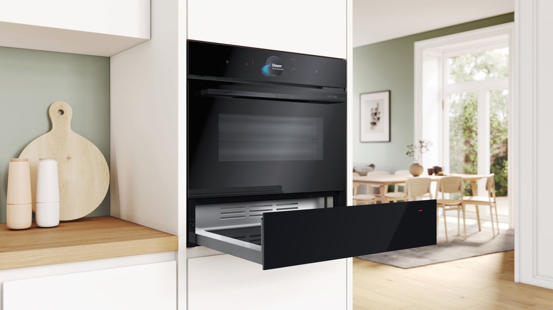 Built-in warming drawer and oven in a modern kitchen with a dining area