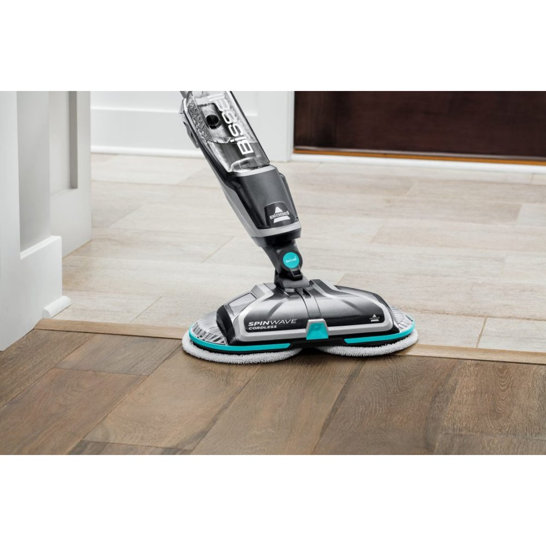 A BISSELL SpinWave Cordless mop cleaning a floor with wood and tile sections