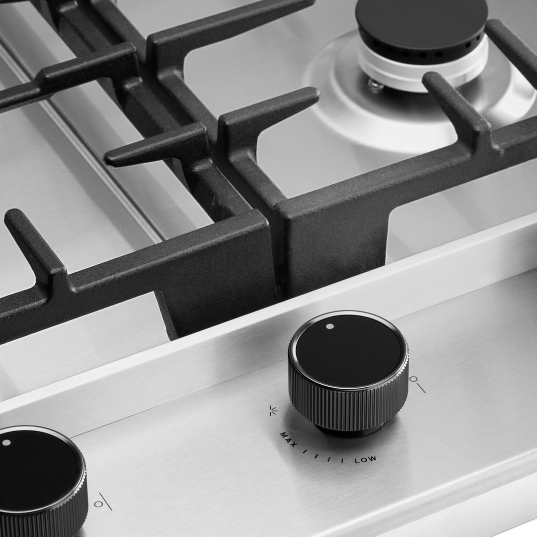Close up of a gas cooktop with black grates and control knobs