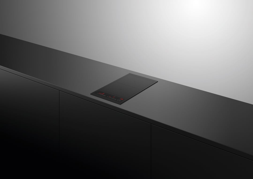Black induction cooktop built into a dark countertop in a modern kitchen