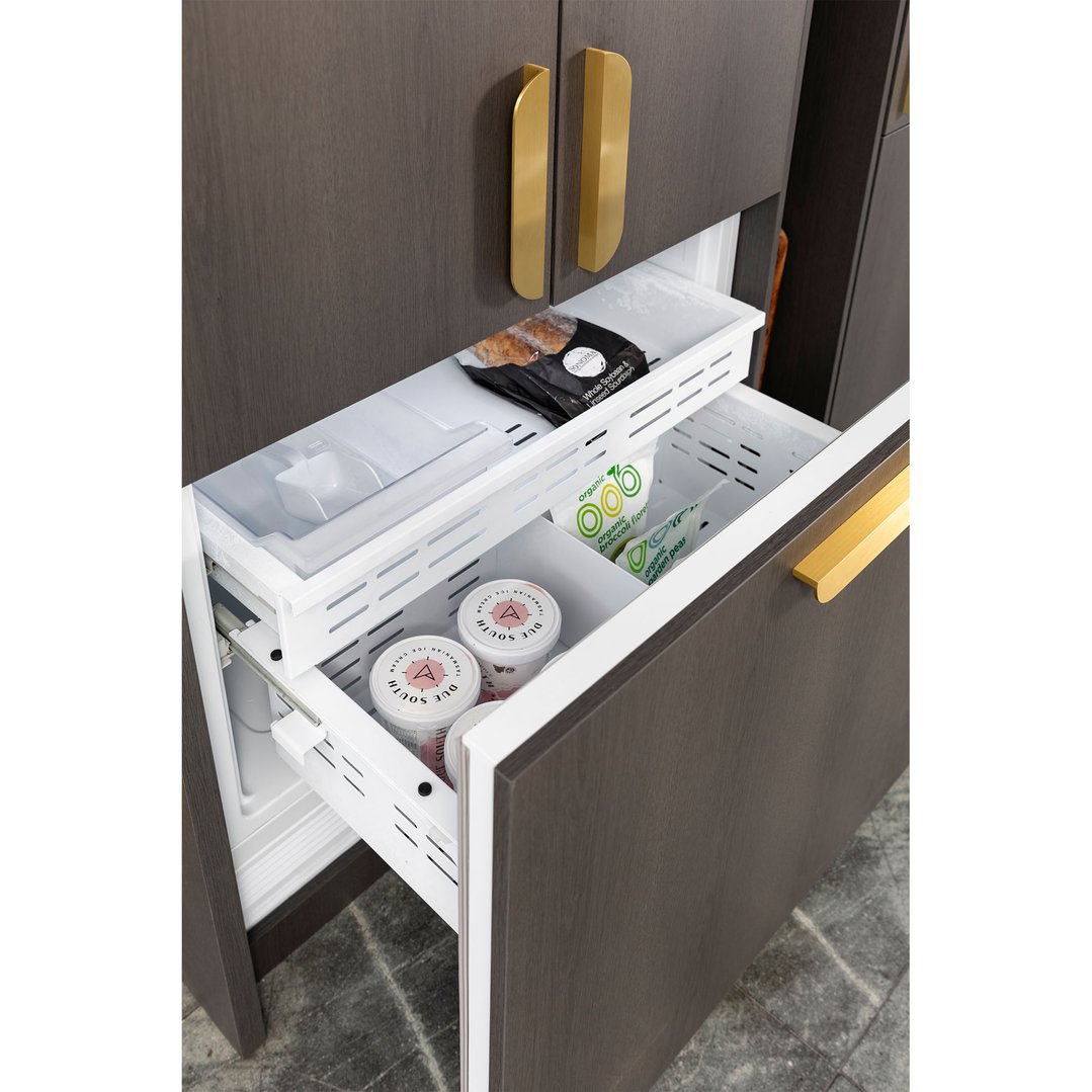 Open integrated French door fridge drawers filled with frozen food items