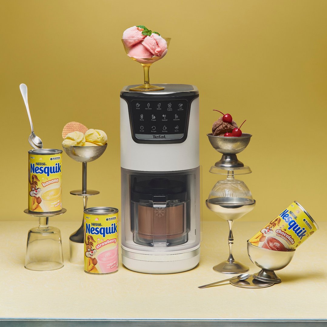 Ice cream maker with ice cream and Nesquik cans on a yellow background